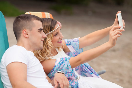 Young couple taking selfie with digital tablet while relaxing on the beach
