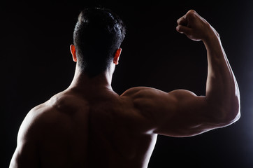 Muscular man posing in dark studio