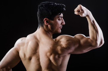Muscular man posing in dark studio