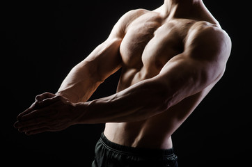 Muscular man posing in dark studio