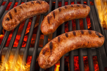 Juicy grilled sausages sizzling over a fiery barbecue, with bold grill marks and vibrant flames. A...