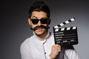 Young caucasian man with clapperboard against gray