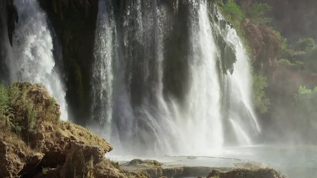 Wide slow motion, panning shot of waterfall in rocky landscape / Havasupai, Arizona, United States