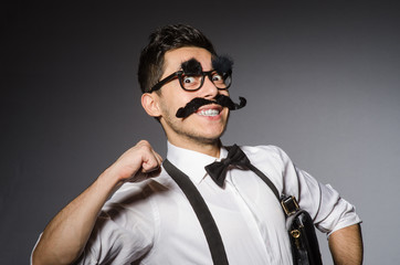 Young caucasian man with false moustache against gray