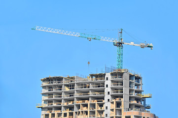 Crane and building construction site against blue sky
