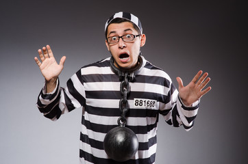 Young prisoner in chains against gray