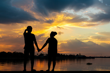 Fototapeta premium Silhouette of couple beside the river with beautiful sunset