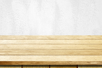 Empty wooden table over white cement wall background