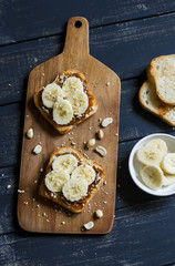 sandwich with peanut butter, banana and peanuts, served on the Board, on a wooden surface