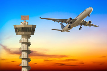 Commercial airplane take off over airport control tower at sunse