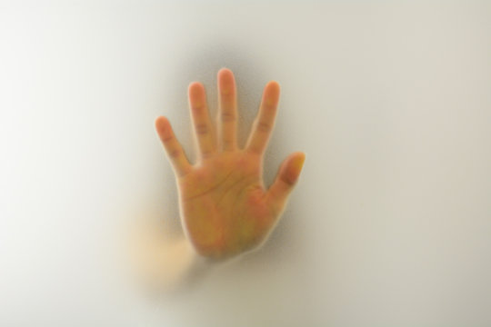 Woman's hand behind blurry glass