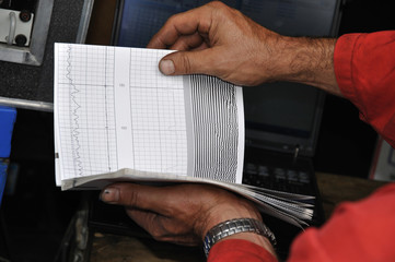 Oil engineer checking data during a swabbing job at an oil well