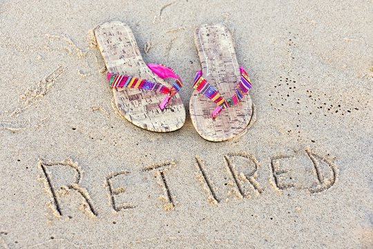 flip-flops in beach sand with retirement message