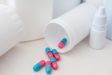 Pills spilling out of pill bottle with medicine background