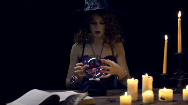 Young witch predicting the future with crystal ball  