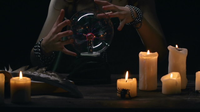 Hands of witch practicing magic with crystal ball 