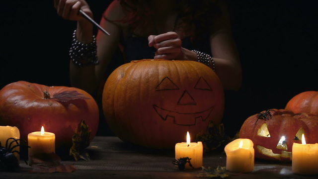 Hands of witch carving Halloween pumpkin  