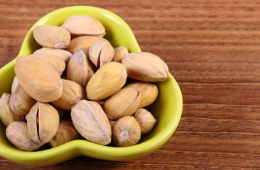 Pistachio nuts in bowl on wooden table, healthy eating