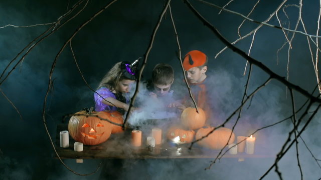 Evil kids conjuring over boiling cauldron on Halloween