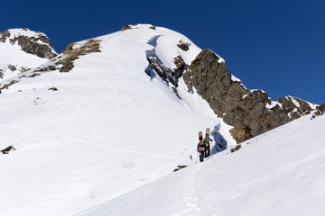 Naklejka na ściany i meble Snowboarders walking uphill for freeride