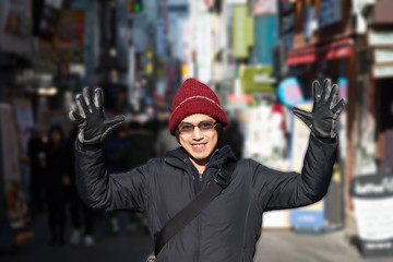 Asian male in winter hat in jacket raise hands chill out around