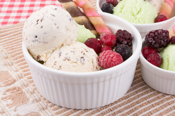 Ice cream with mixed fruits in white bowl with waffle sticks.