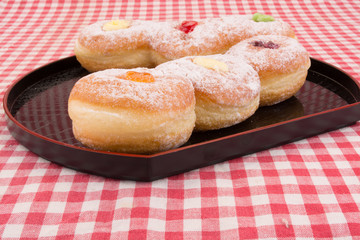 Donuts bun in a plate on red stripe table cloth.