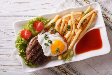 beefsteak, fried egg and potatoes on a plate. horizontal top view

