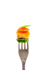 a piece of fried meat with vegetables on a fork isolated on a white background vertical