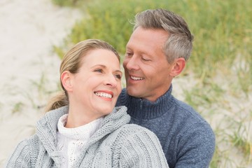 Fototapeta premium Smiling couple sitting on the sand