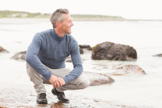 Man Crouched Down On A Large Rock