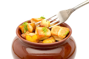 Fried potatoes with chunks of meat in a clay pot on isolated a white background