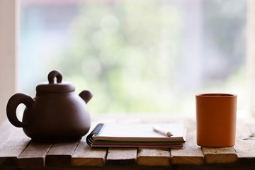 vintage old teapot clay cup and notebook  on wooden table