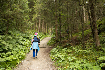 Obraz premium mother with baby in carrier hiking on the forest track
