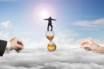 Two hands pulling rope businessman balancing on hourglass