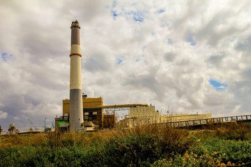 Fototapeta na wymiar Small power plant using gas on dark stormy cloudy sky background