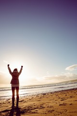 Fototapeta premium Rear view of woman looking at the sea with hands up