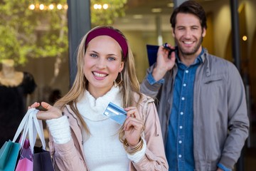 Smiling couple with shopping bagsshowing credit card