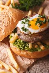 Rustic sandwich with beefsteak, fried egg and fries close-up. vertical
