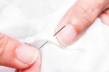 women's hands while sewing white cloth