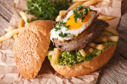 Sandwich with steak, fried egg and French fries close-up. Horizontal
