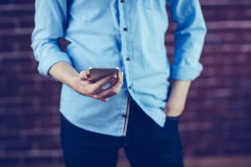 Midsection of man holding smartphone