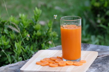 carrot juice and carrot segments on a wooden background