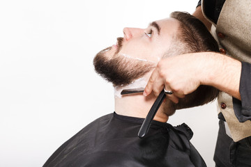 Hairdresser shaving handsome man, on white background