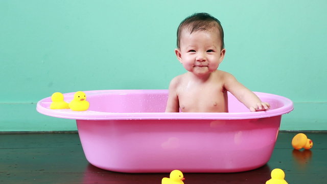Cute little baby bathed in a pink bath