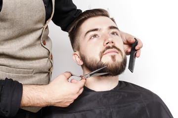 Hairdresser cut the beard of handsome satisfied client