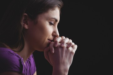 Woman praying with hands together - obrazy, fototapety, plakaty