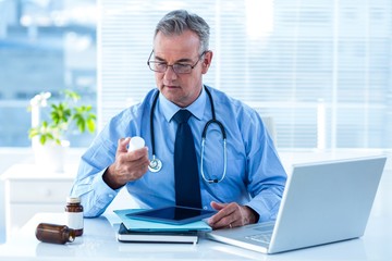 Fototapeta premium Male doctor holding pill bottle in clinic