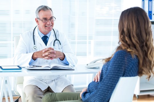 Male doctor discussing with pregnant woman in clinic
