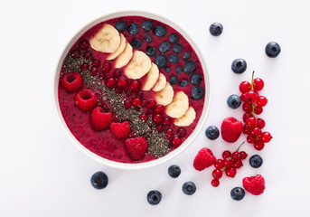 berry smoothie bowl with chia seeds, bananas, blueberries, currant and raspberries on white...